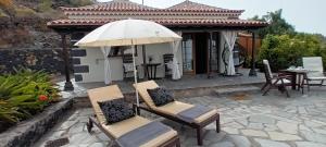 蒂哈拉费Bungalows Aldani的庭院配有椅子、遮阳伞和桌子。