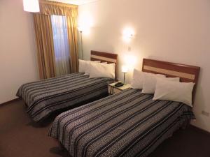 阿雷基帕Hotel San Andres的酒店客房设有两张床和两盏灯。