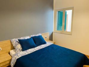 斯卡莱阿Marina Apartament的一间卧室设有蓝色的床和窗户。