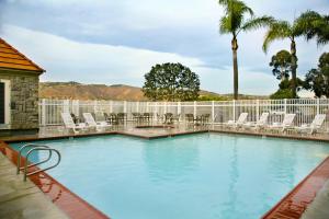 安纳海姆约巴林达/阿纳海姆山艾瑞斯套房酒店的一个带椅子和棕榈树的大型游泳池