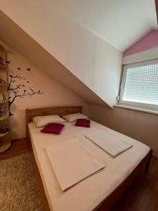 萨拉热窝Holiday Home Hodo的一间卧室配有一张带红色枕头的床和一扇窗户