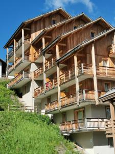 瓦尔residence avec piscine ,chalet des rennes的山丘上带木制阳台的公寓楼