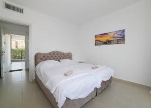 提比里亚אצולת הים - טבריה的一间卧室配有一张带白色床单的大床