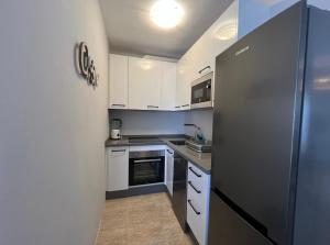贝纳尔马德纳Las Palmeras的厨房配有白色橱柜和黑色冰箱。