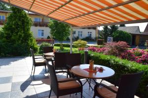 Klietz赛布里克兰德加特酒店的一个带桌子和椅子的庭院,位于橙色伞下