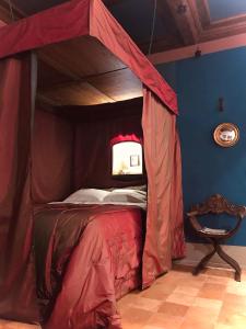 乌尔比诺圣波罗1544仿古客房住宿加早餐旅馆的一张天蓬床,位于带椅子的房间里