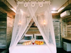 蓝梦岛纳努克斯小屋酒店的卧室配有带白色窗帘的天蓬床