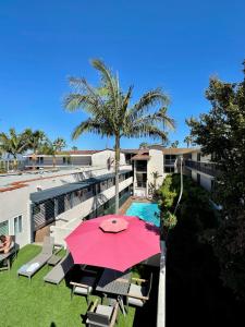 圣巴巴拉Beachside Inn的一个带粉红色遮阳伞和游泳池的庭院