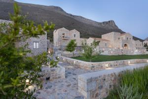 阿里奥波利斯Armantanis Luxury Suites的一座大石头房子,后面有一座小山