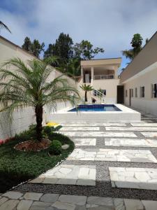 圣塞巴斯蒂安Recanto da Ivete的房子旁的院子中的棕榈树