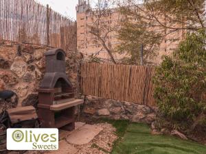 阿拉德Olives sweets的后院设有砖墙和户外烧烤架