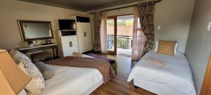 布隆方丹Solo Gracia Guesthouse的一间带两张床、一台电视和一个阳台的卧室