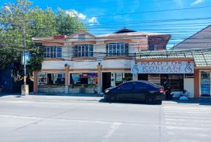 伊洛伊洛RedDoorz @ Plaza La Paz Iloilo City的停在街道上建筑物前面的汽车