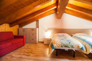 Forni di Sotto多洛米蒂大酒店 的一间卧室配有一张床和一张红色的沙发
