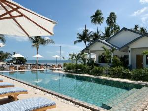 苏梅岛Pearl of Samui Resort的度假村的游泳池,配有椅子和遮阳伞