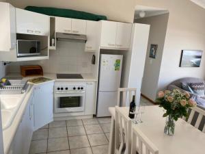 赫罗德斯湾Herolds Bay Accommodation - Hiers Ons Weer Upstairs的厨房配有白色橱柜和鲜花桌