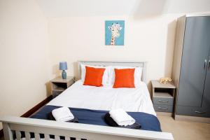 DouglasRigside House的卧室配有带橙色枕头的白色床