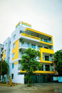 古尔冈Lime Tree Luxury Studio - Service Apartment Near Artemis Hospital ,Gurgaon的一座黄色和白色的建筑,前面有一棵树