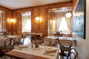 博尔米奥Hotel Rezia的用餐室设有桌椅和木墙