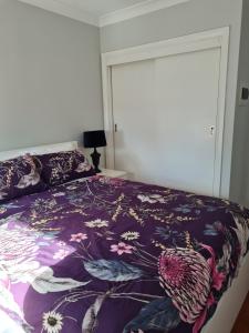 沃加沃加Alkion Villa的一间卧室配有一张带紫色棉被的床
