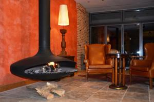 奥格斯堡Ringhotel Alpenhof - Patchworkhotel的壁炉,配有两把椅子和一张桌子