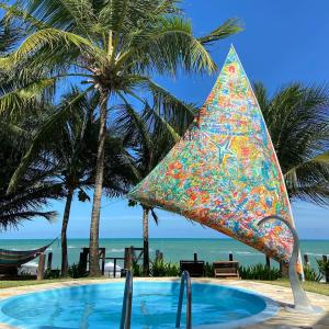 普拉亚多斯卡内罗斯As Coloridas的棕榈树旁的游泳池及其色彩缤纷的遮阳伞