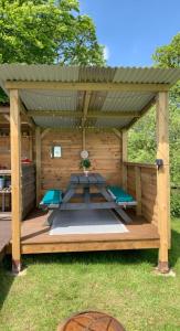 LlangrannogYurt glyncoch isaf farm的木制凉亭配有野餐桌和长凳
