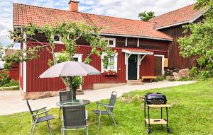 赖特维克Cozy Home In Rttvik With Kitchen的红色建筑前的桌椅和雨伞