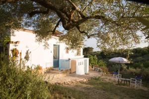 卡马尔莱斯Casa Rural Delta del Ebro Ecoturismo的白色的房子,配有桌子和雨伞