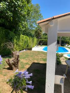 CambreAgradable chalet rústico的一个带桌子和紫色花卉的花园和一个游泳池