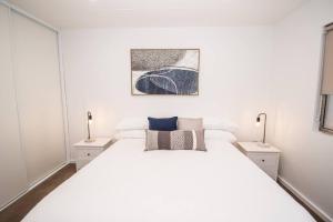 布罗肯希尔Willow Court Unit 2的白色卧室配有白色的床和两盏灯。