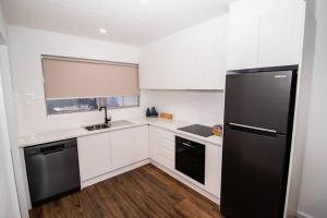 布罗肯希尔Willow Court Unit 4的厨房配有白色橱柜和黑色冰箱。