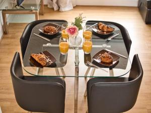 伯明翰Lovely 1 Bedroom Apartment - Bham City Centre的玻璃桌,带食物和橙汁的盘子