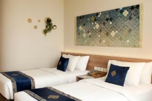 芝卡朗Antero Hotel Jababeka的酒店客房设有两张床,墙上挂有绘画作品