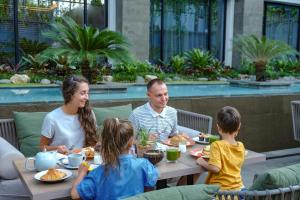 沙努尔Holiday Inn Bali Sanur, an IHG Hotel的坐在餐桌旁吃食物的家庭