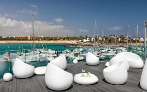 卡勒达德福斯特Barceló Fuerteventura Royal Level的码头上一群白色椅子,有船