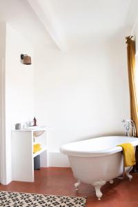 布里尼奥勒Maison Sumiane的浴室配有白色浴缸和地毯。
