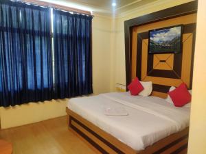 达兰萨拉Hotel Amandeep的一间卧室配有一张带红色枕头的床和一扇窗户