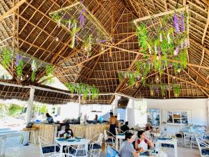 南威Badolina Bungalows的一间设有桌子和椅子的稻草屋顶餐厅