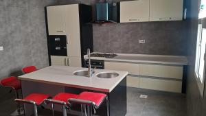 塞拉莱Luxury Garden Villas Complex的厨房配有水槽和4张红色凳子