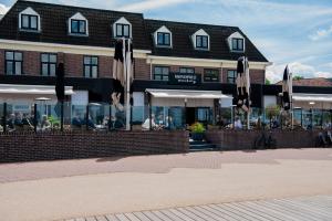 哈尔德韦克Restaurant & Hotel Monopole Harderwijk的大楼前带遮阳伞的餐厅