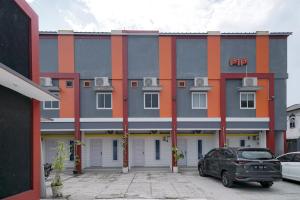 MargakayaUrbanview Hotel Pondok Indah Pringsewu的一座灰色和橙色的建筑,前面有停车位