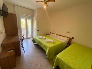 里米尼Hotel Dream的一间卧室设有两张带绿床单的床和窗户。
