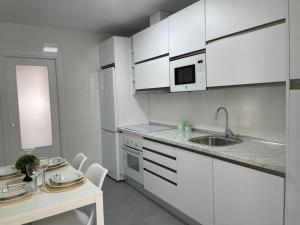 马拉加piso recinto ferial en teatinos的厨房配有白色橱柜、水槽和桌子