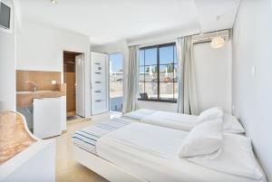 法里拉基Mando Living -Faliraki的白色的卧室设有一张大床和一个窗户