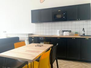 波城Pau's Appart - Pau Centre的厨房配有黑色橱柜和一张带黄色椅子的木桌