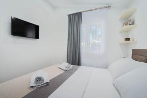 拉扎尼Villa Marijo的一间白色卧室,配有床和电视