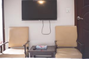 卡拉奇GOHO Rooms Badar的墙上配有电视的房间里设有两把椅子