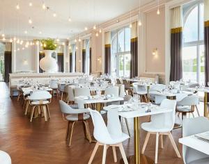 孔特雷克塞维尔Hôtel Cosmos & Spa的一间设有白色桌子和白色椅子的餐厅
