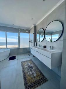 开普敦Bay Reflections Camps Bay Luxury Serviced Apartments的一间带大镜子、浴缸和水槽的浴室